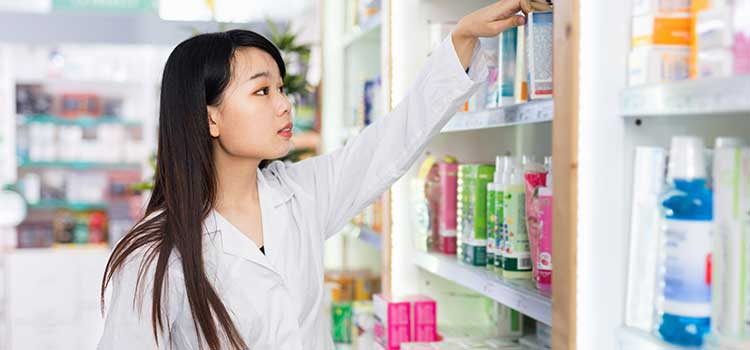 pharmacy technician pulls stock from shelf in california pharmacy