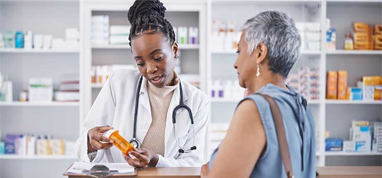 pharmacy technician explains dosage instructions to customer at pharmacy desk